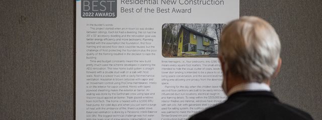 a man is reading the poster of the Residential New Construction "Best of the Best" award